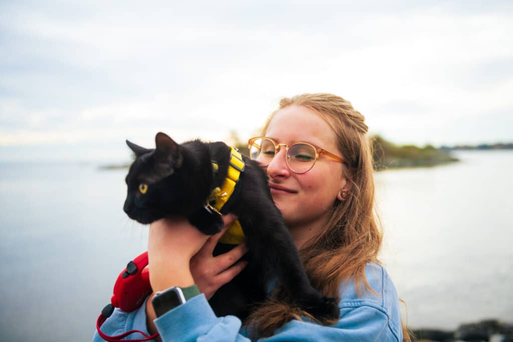 Girl holding her black cat, giving him a kiss